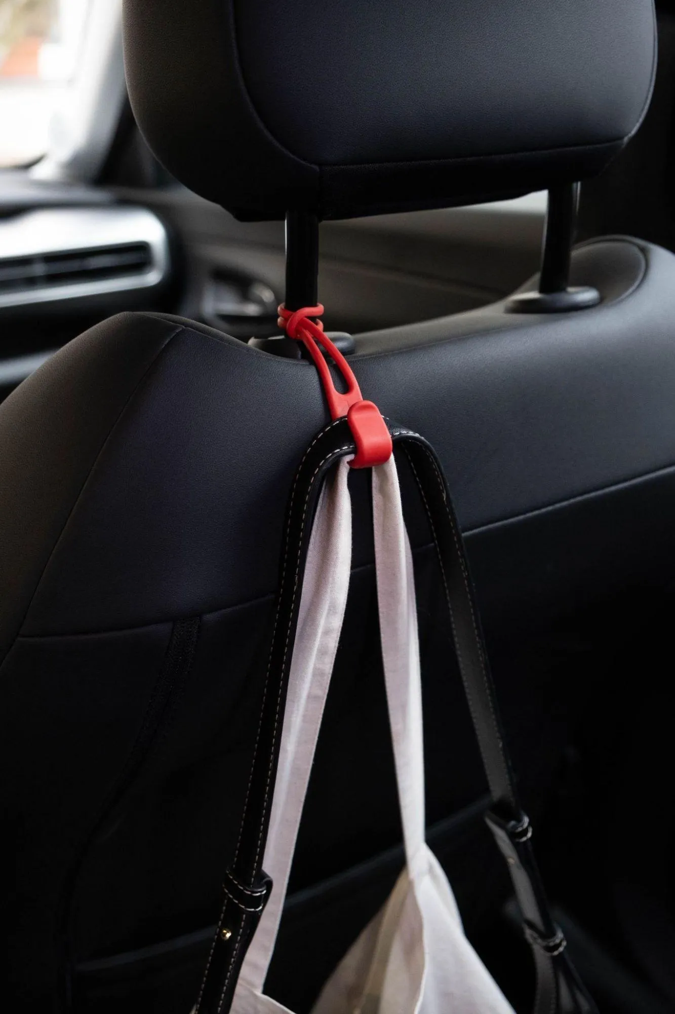 Red Stowey hook holding a bag on a car headrest