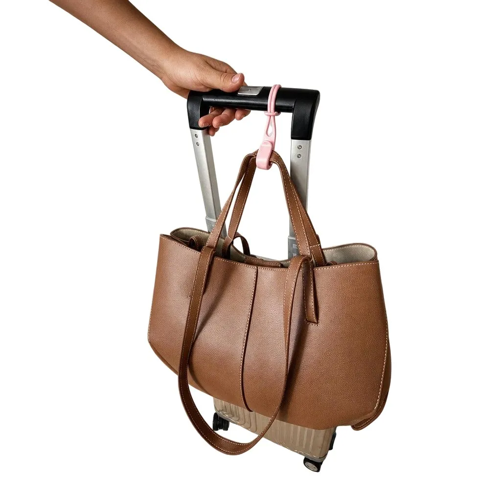 Pink Stowey hook holding a leather handbag on a suitcase handle