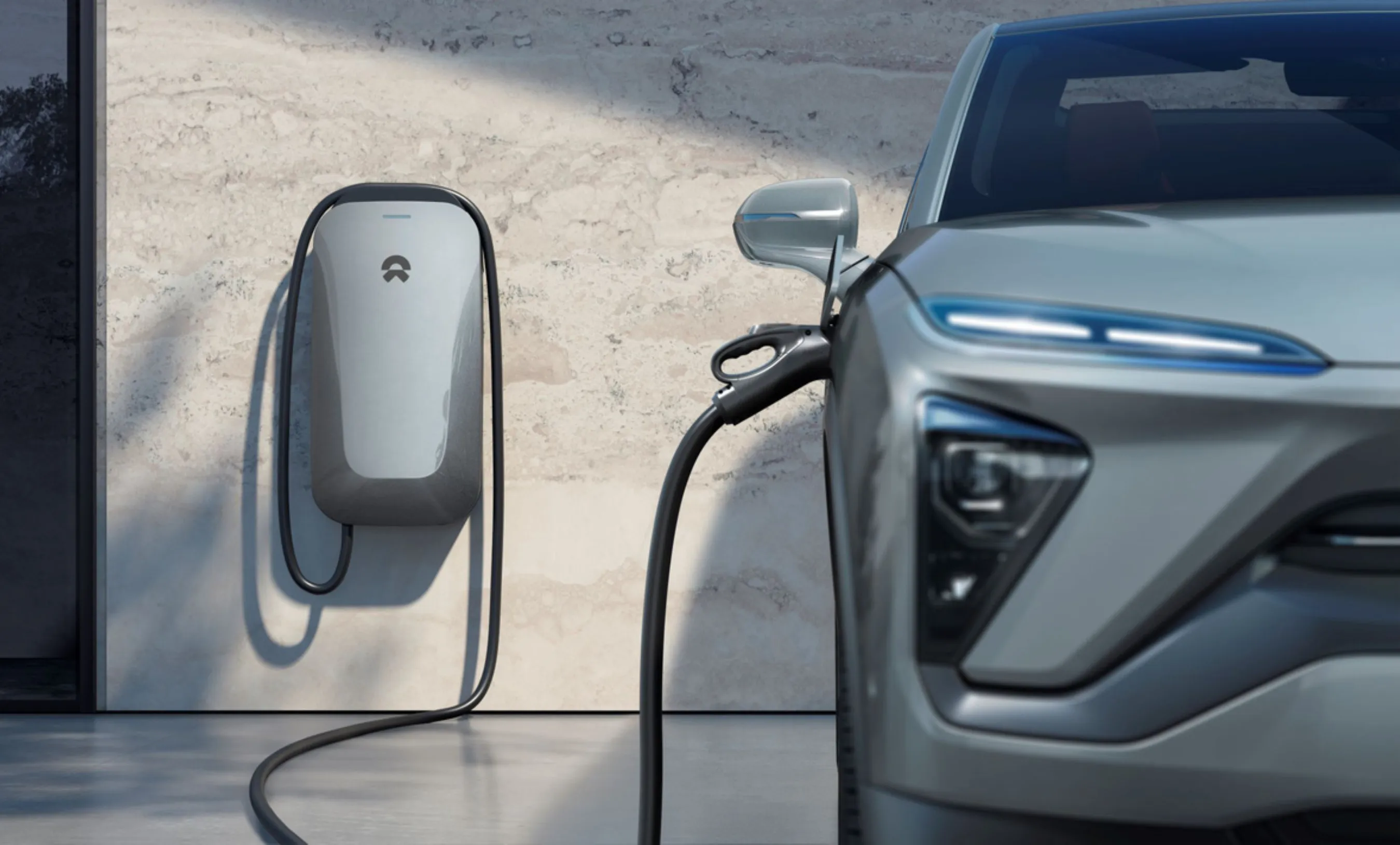 NIO home charger on a wall next to a charging NIO car