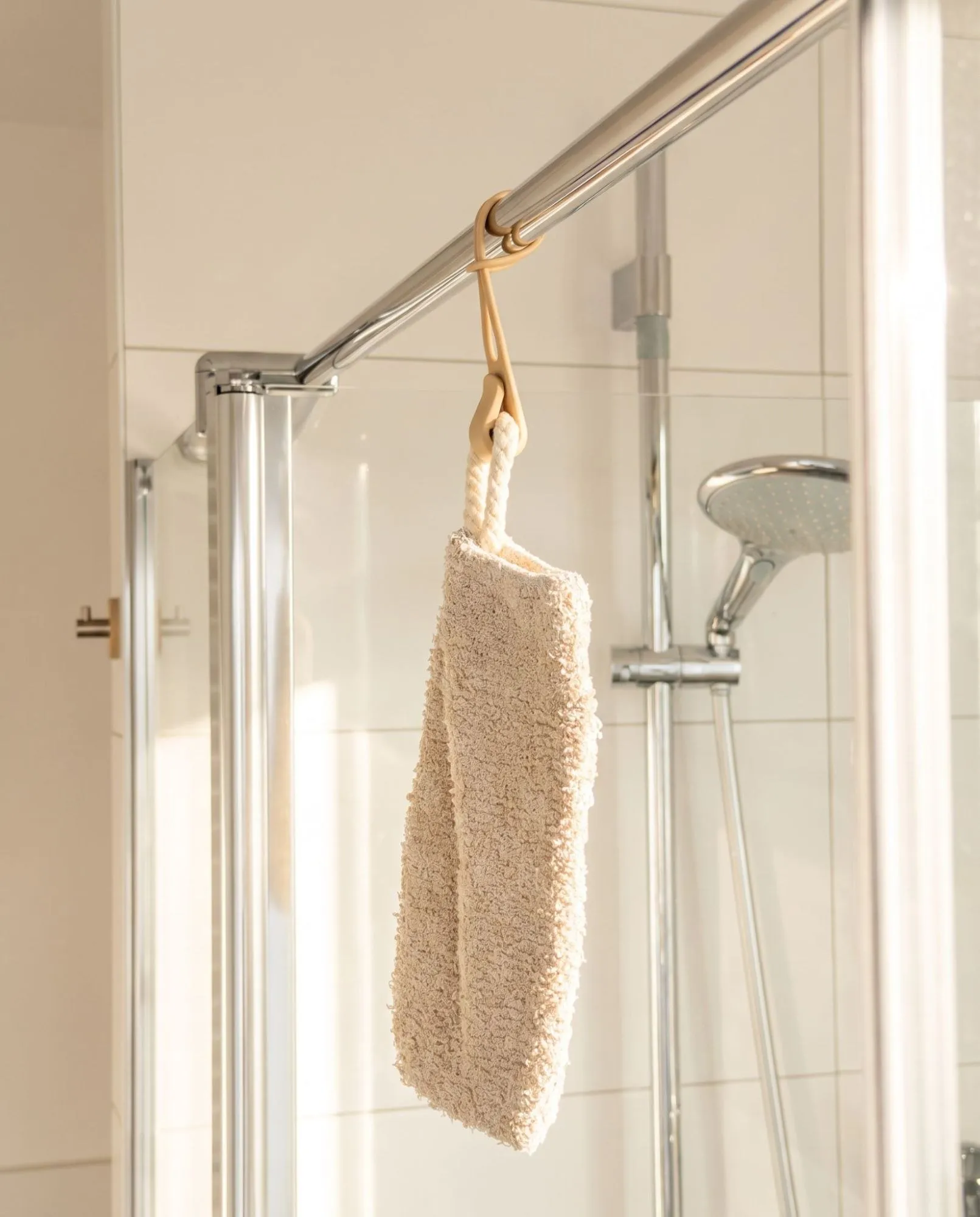 Beige Stowey hook holding a washcloth on a shower rail