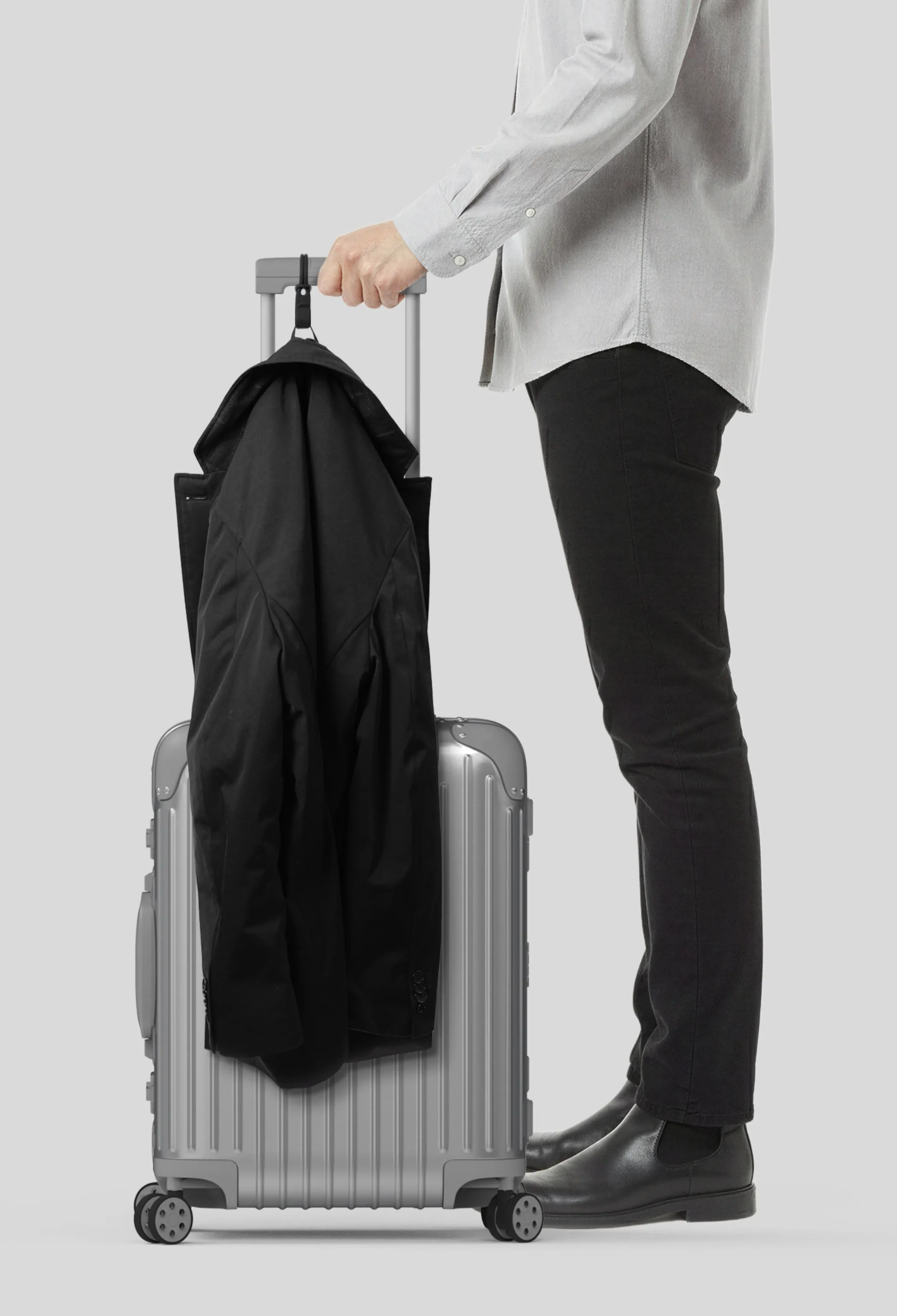 Traveller with a coat hanging from a Stowey hook on the suitcase handle